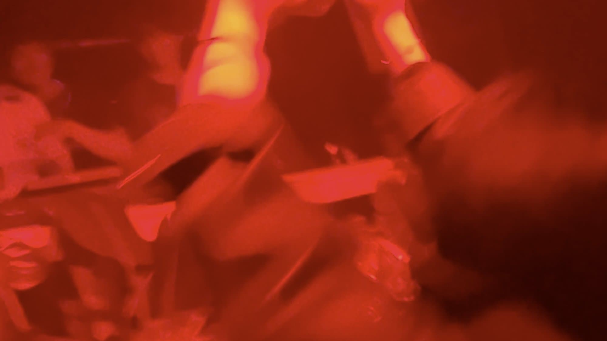 Dancers dissolved in deep red light, arms up, close to the booth